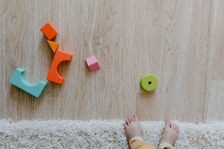 Niña y niño jugando con bloques de colores en el piso de la sala